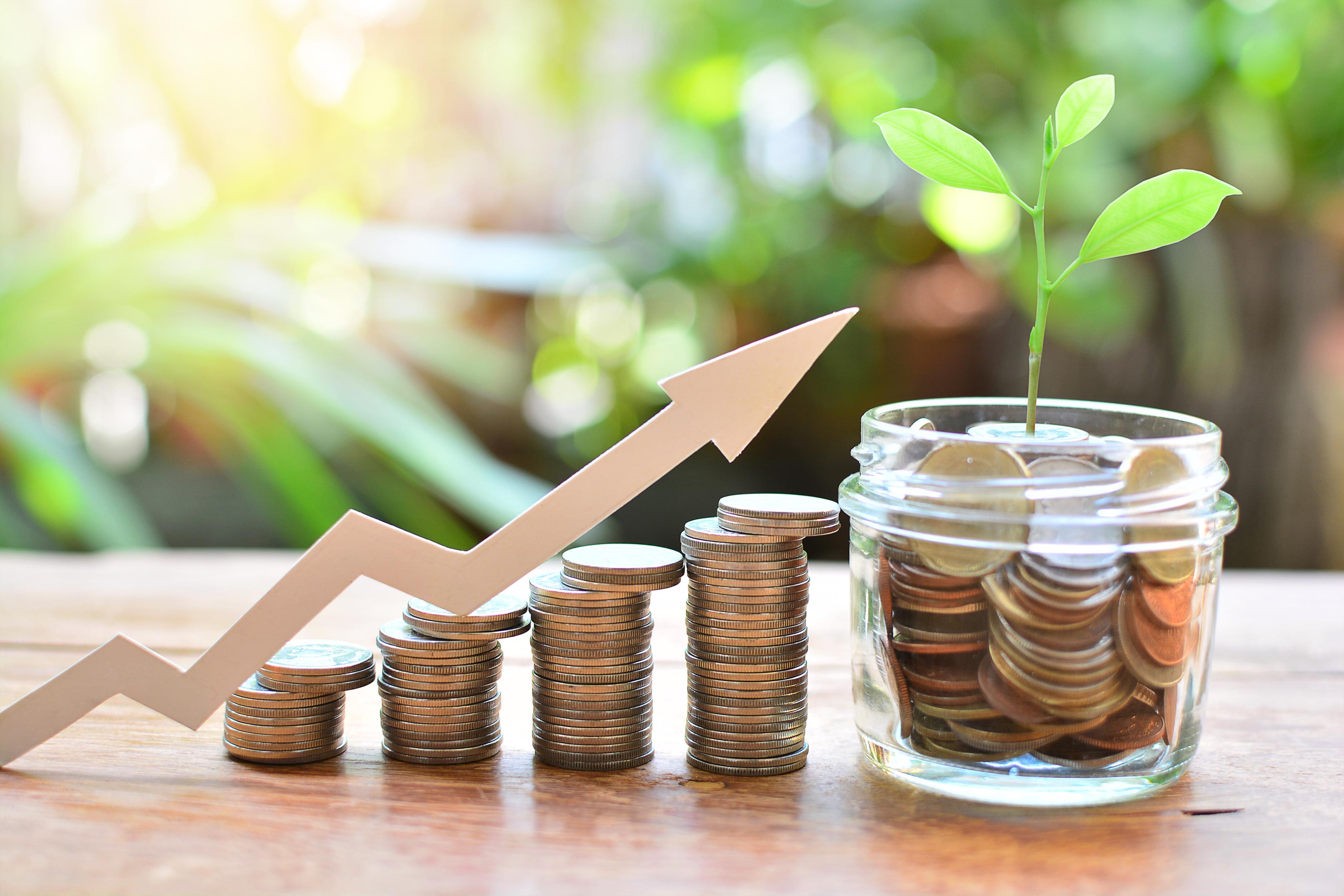 Stacks of coins with coins in a jar and an arrow showing growth